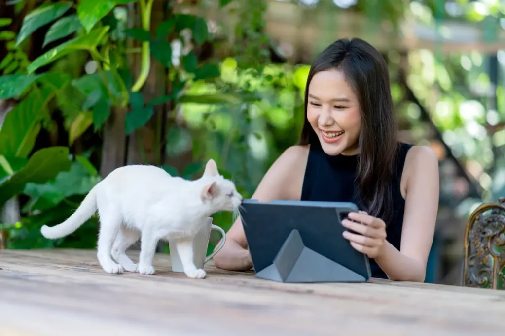 Uma moça com seu gato, procurando no seu tablet videop para gatos.
